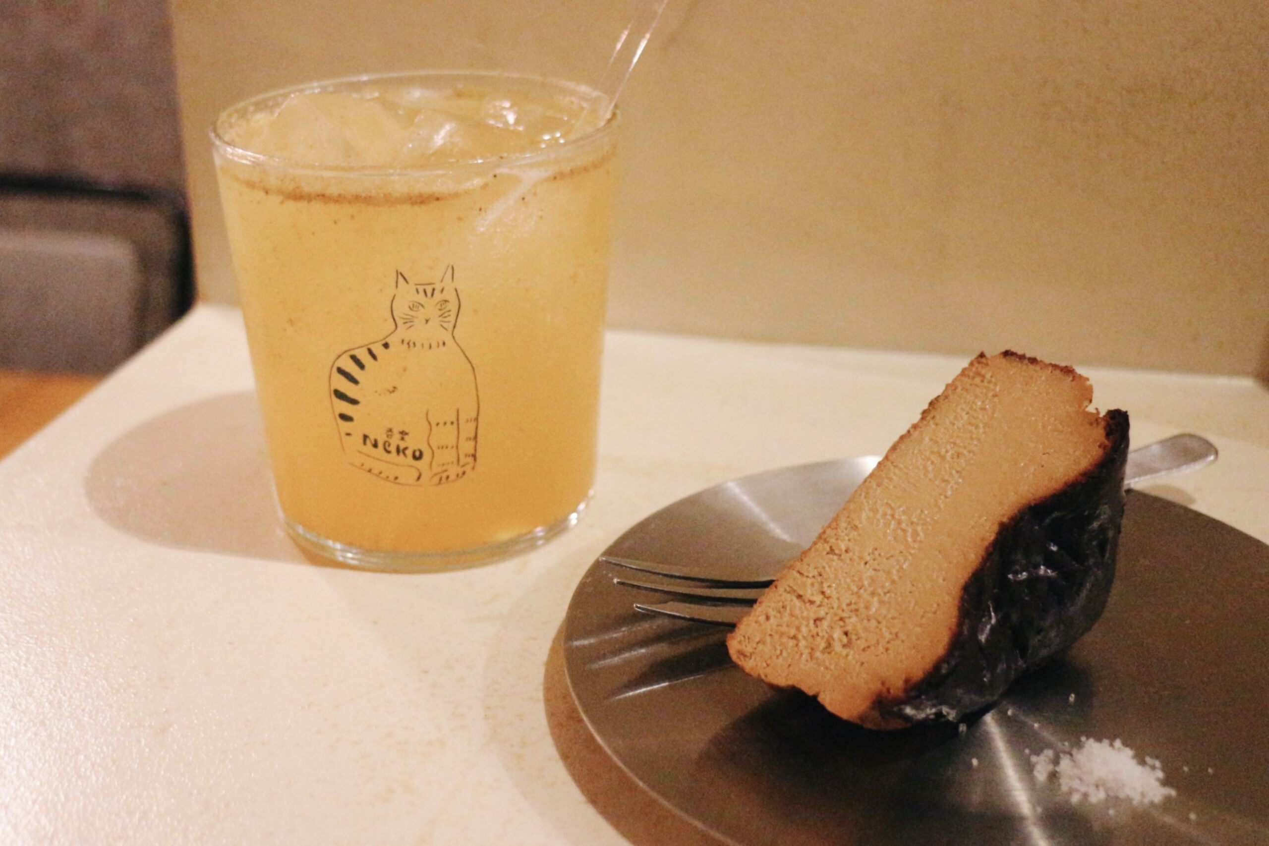 吉祥寺の居酒屋「呑楽Neko」猫のイラストが描かれたグラスに入ったカクテルと器にのったバスクチーズケーキ