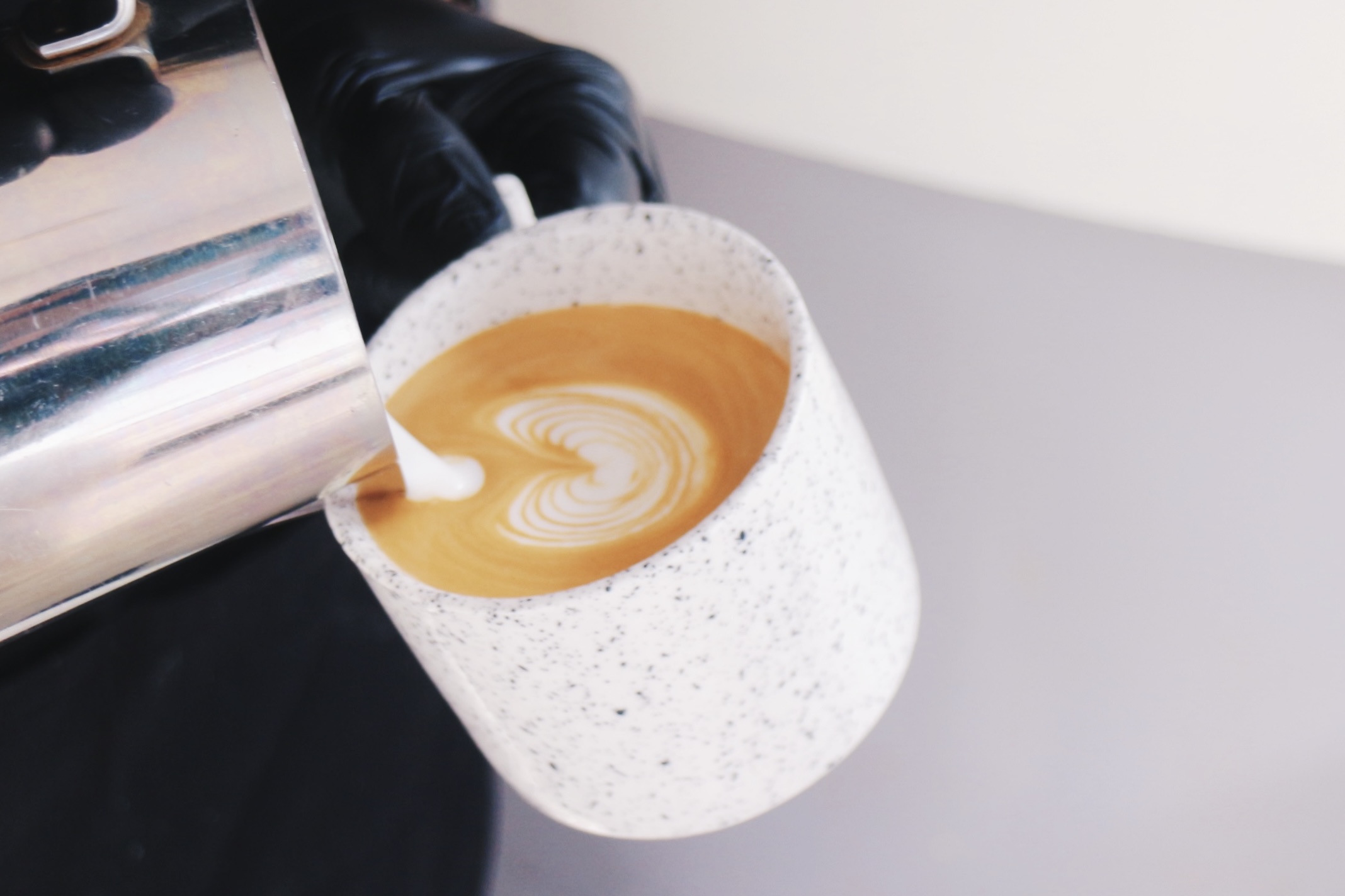 マグカップにミルクを注ぎラテを作る様子